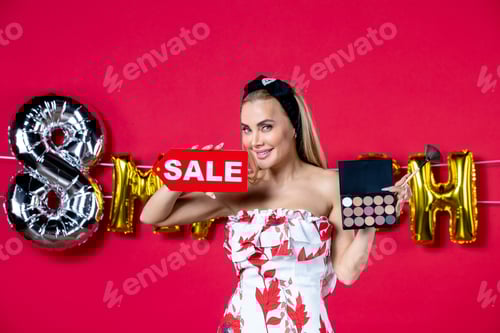 Preview: front view young female holding eyeshadow palette and sale nameplate on red background gloss skin