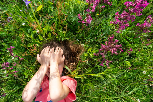 Preview: Portrait of a child girl in summer lying in the grass and wildflowers with heels and palms. summer t