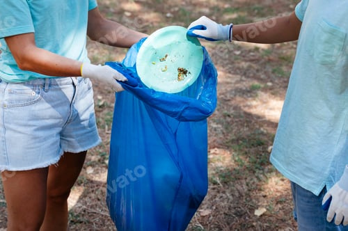 Preview: Volunteer woman and boy collecting garbage in a park.