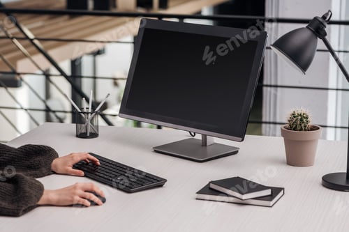 Preview: cropped view of woman using computer at workplace with stationery