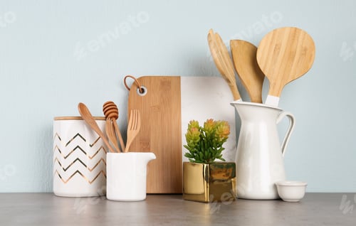 Preview: Potted plant and set of kitchenware on grey table near light wall. Modern interior design