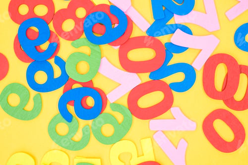 Preview: Top view of the colorful wooden numbers scattered on a yellow surface