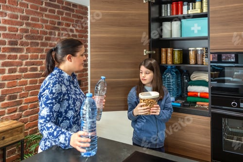 Preview: Mother and daughter storing food and water in kitchen pantry for emergencies or natural disasters