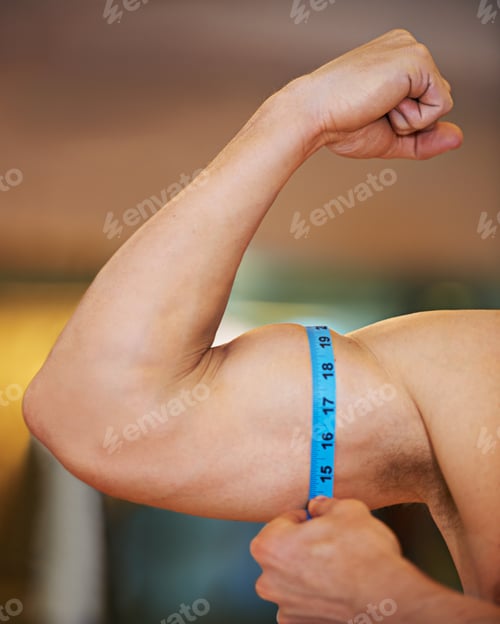 Preview: Impressive bicep on display. Muscular man measuring his bicep with a measuring tape.