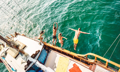 Preview: Top view of trendy adventurous friends jumping from sailboat on sea ocean trip