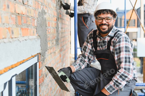 Preview: Smiling construction worker plastering brick wall