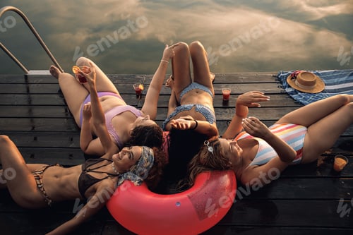 Preview: Group of female friends enjoying a summer day laying on the pier at the lake.