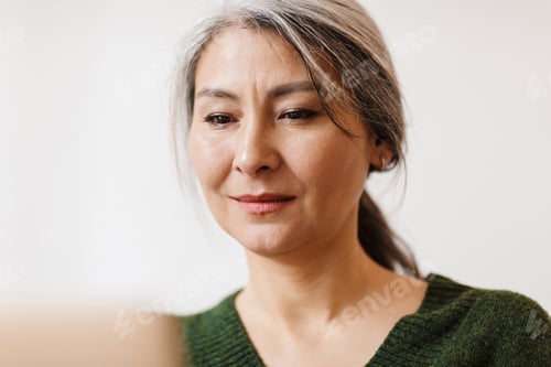 Preview: Beautiful grey-haired woman using laptop computer indoors.