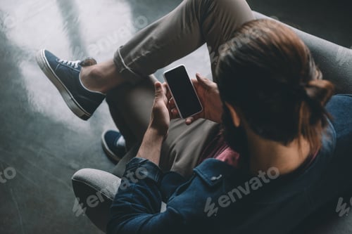 Preview: top view of man with hair bun using smartphone