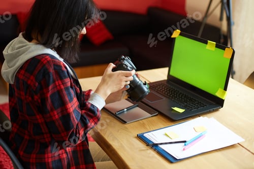 Preview: Photographer female working in a creative office holding camera, at desk and retouch photo