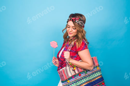 Preview: attractive young woman with lollipop in hand on blue background with copy space