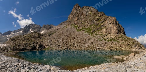 Preview: Clear mountain lake reflecting rugged cliffs and snow capped peaks in alpine landscape