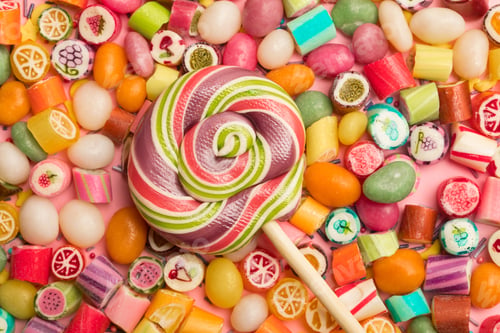 Preview: top view of bright delicious multicolored caramel candies and swirl round lollipop on wooden stick