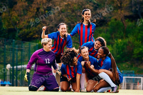 Preview: Team of happy female players celebrating victory after soccer match.