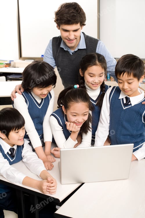 Preview: Students and teacher gathered around a computer in the classroom
