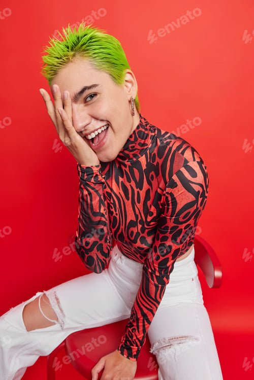 Preview: Glad emo girl with trendy haircut keeps hand on face tries to hide her emotions smiles sincerely wea