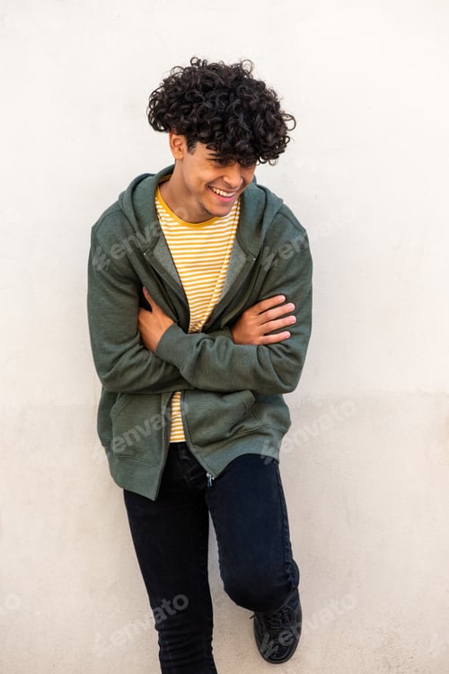 Preview: laughing young man with arms crossed by white wall