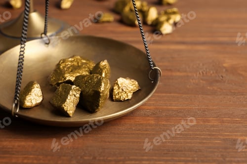 Preview: Scale pan with gold lumps on wooden table, closeup. Space for text