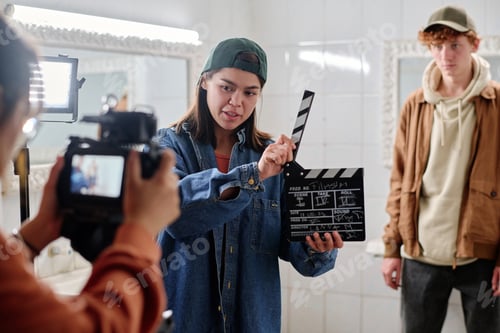 Preview: Filmmaker Holding Clapboard with Crew Member Observing