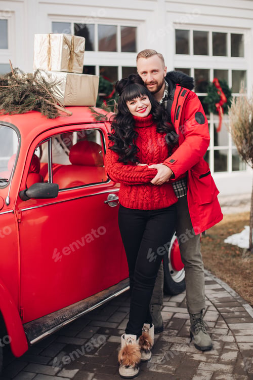 Preview: Cheerful smiling couple at red vintage car.