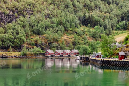 Preview: Red houses by Lysefjord surrounded by lush green forest on a sunny day in southern Norway