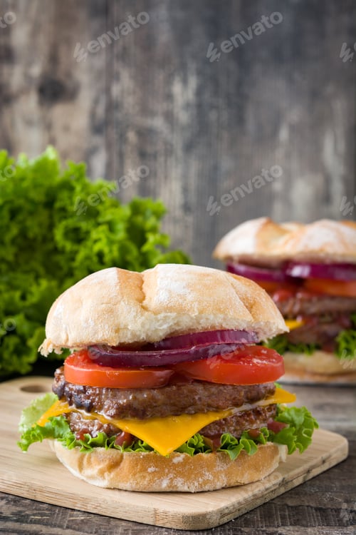 Preview: Delicious cheeseburger with lettuce, tomato, and red onion on rustic wooden background