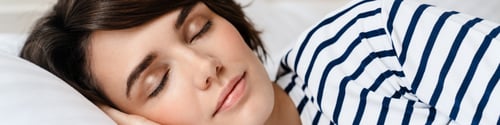 Preview: Happy beautiful girl sleeping while lying in bed at home