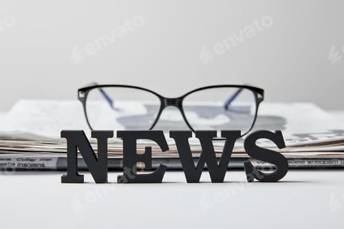 Preview: selective focus of news lettering near glasses and newspaper on white