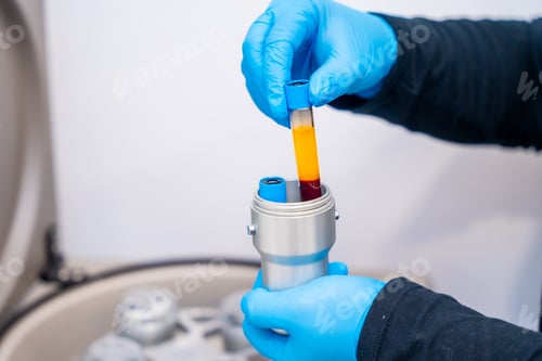 Preview: Technician holding samples of blue next to centrifuge machine