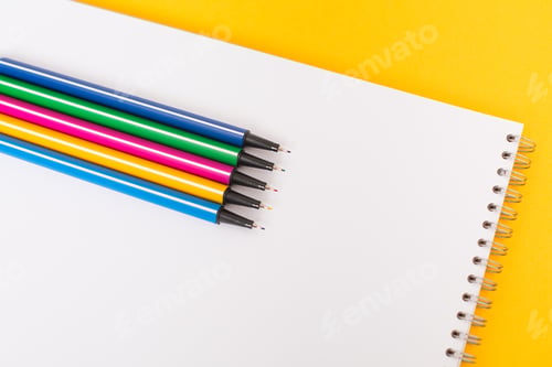 Preview: Colored pens lie on sheets of white paper on a blue background. Place for text