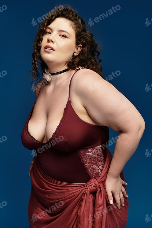 Preview: Stylish young woman posing gracefully against a vibrant blue backdrop in trendy attire