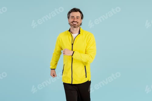 Preview: Happy sportsman running wearing yellow jacket on blue background