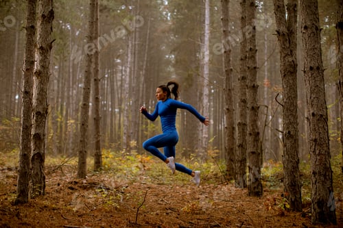 Preview: Young woman taking high jump on the forest trail at autumn