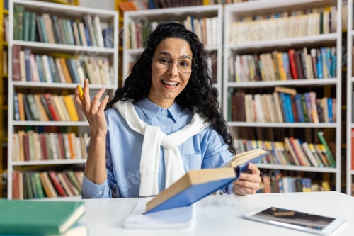 Preview: Smiling librarian explaining book content in a library
