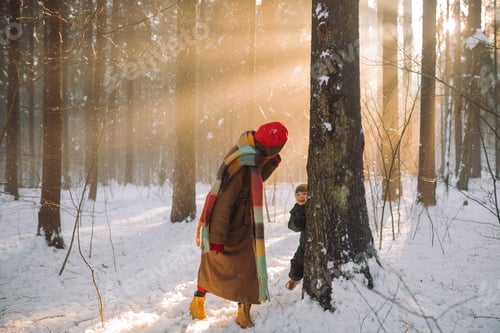 Preview: Mom playing hide-and-seek with her little son in nature on a snowy winter day.