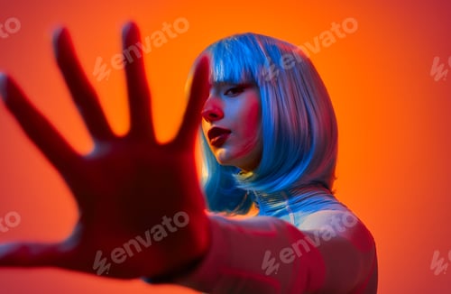 Preview: Extravagant female covering camera with hand in studio