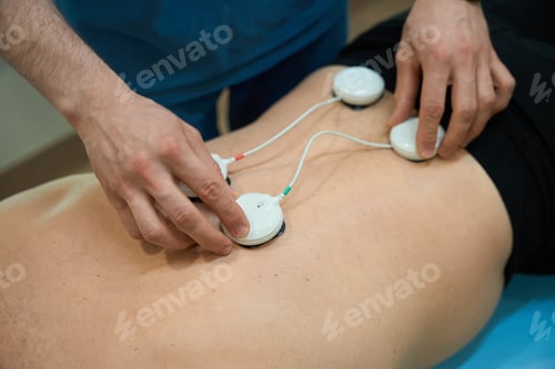 Preview: Physical therapist getting adult person ready for electrical muscle stimulation