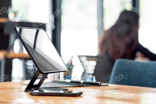 Preview: Portable tablet on stand and smartphone on wooden table.
