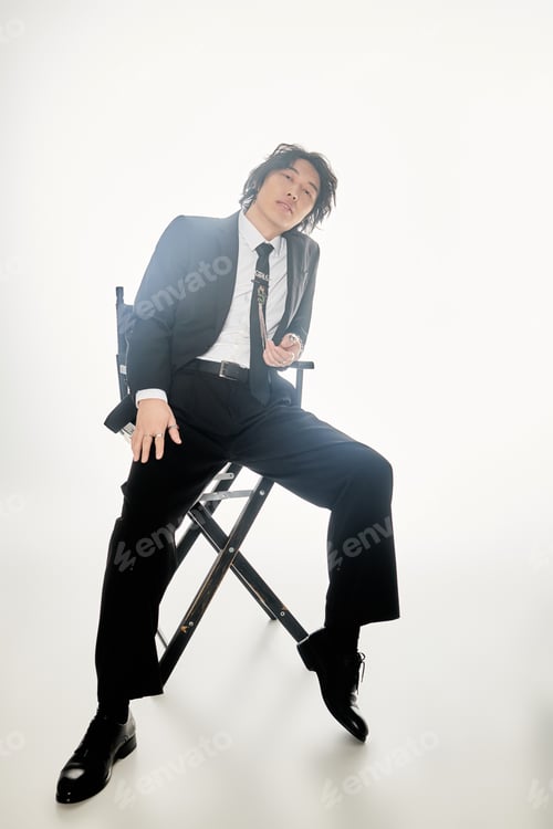Preview: Young man in stylish suit poses confidently on a chair in a chic urban setting