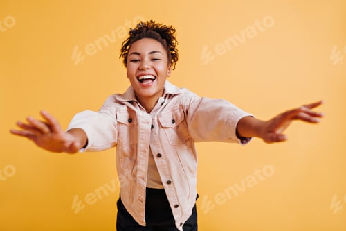 Preview: Selective focus of laughing black girl posing with outstretched hands. Front view of happy african