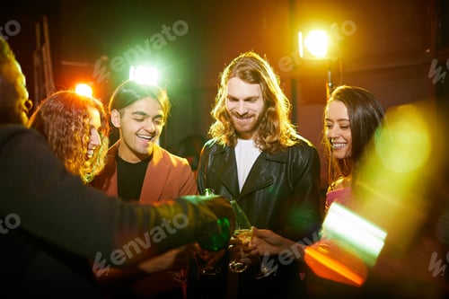 Preview: Excited friends pouring champagne in nightclub