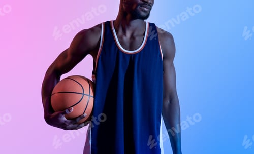 Preview: Closeup of black basketball player holding ball in neon lighting