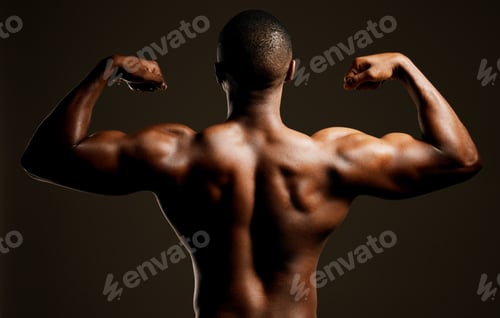 Preview: Rearview studio shot of a fit young man flexing against a black background