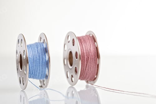 Preview: spools of blue and pink thread on a white background