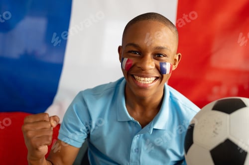 Preview: Portrait of happy african american male teenager sitting with flag of france and football