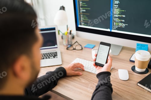 Preview: Software developer is coding on his smartphone and computer