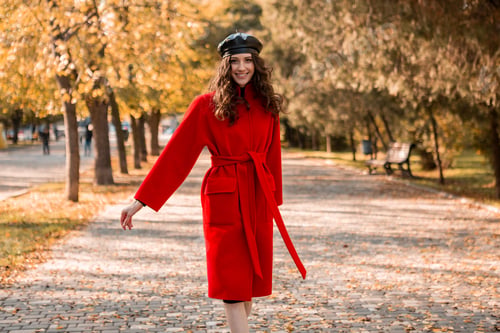 Preview: attractive stylish woman walking in park dressed in warm red coat