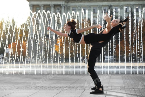 Preview: Beautiful young couple practicing dance moves near fountain outdoors