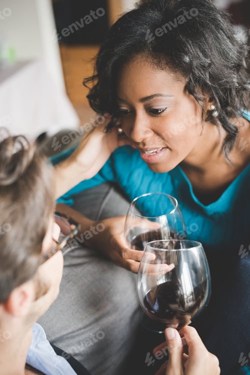 Preview: Young handsome mixed race couple in their house having a glass of red wine