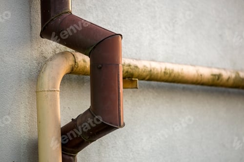 Preview: Close-up detail of old dirty painted yellow natural gas and brown gutter rain water pipes fastened